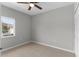 An empty bedroom with light tile floors, a ceiling fan, and a window overlooking neighboring buildings at 9519 Newdale Way # 202, Riverview, FL 33578