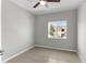 An empty bedroom with tile floors, a ceiling fan, and a window overlooking neighboring buildings at 9519 Newdale Way # 202, Riverview, FL 33578