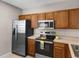 Stylish kitchen featuring stainless steel appliances, wood cabinets, and tile flooring at 9519 Newdale Way # 202, Riverview, FL 33578