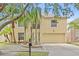 Charming two-story home featuring a two car garage, light yellow paint and mature landscaping and palm trees at 10311 Frog Pond Dr, Riverview, FL 33569