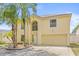 Charming home exterior with a well-manicured lawn, mature palm trees, and a two car garage at 10311 Frog Pond Dr, Riverview, FL 33569