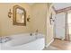 Relaxing main bathroom with a tub, decorative mirrors, wall sconces and an open doorway at 10311 Frog Pond Dr, Riverview, FL 33569