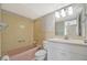 Classic bathroom includes a pink tub, matching tile, and a vanity with ample lighting at 10355 Paradise Blvd # 502, Treasure Island, FL 33706