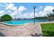Large outdoor swimming pool featuring a brick surround, landscaping, and views of a marina at 10355 Paradise Blvd # 502, Treasure Island, FL 33706