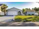 Charming single-story home with a well-maintained lawn, an attached garage, and lush palm trees at 10733 Drummond Rd, Tampa, FL 33615