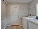 Bright laundry room featuring a full-size washer and dryer, tile floors, and door with hooks at 11121 Hudson Hills Ln, Riverview, FL 33579
