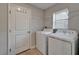 Bright laundry room featuring a full-size washer and dryer, tile floors, and door with hooks at 11121 Hudson Hills Ln, Riverview, FL 33579