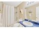 This cozy bathroom features blue counters, a shower with white curtain, and a decorative mirror at 11148 Hollander Ave, Hudson, FL 34667