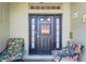 Covered porch showcasing a welcoming front door and cozy seating area with floral cushions at 11148 Hollander Ave, Hudson, FL 34667