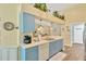 Bright kitchen with blue cabinets, decorative plants, and a view into the living room at 11148 Hollander Ave, Hudson, FL 34667