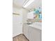 Well-organized laundry room with modern washer and dryer, storage cabinets, and laminate wood floors at 11148 Hollander Ave, Hudson, FL 34667