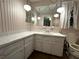 Bathroom with white cabinetry, decorative wallpaper, and large mirror at 11198 58Th Ave, Seminole, FL 33772