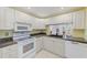 Efficient kitchen with white cabinetry, neutral counters, and convenient pass-through to the dining area at 12300 Vonn Rd # 7107, Largo, FL 33774