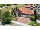 Beautiful home showcasing a tile roof, brick driveway, lush landscaping, and a serene neighborhood pond at 13706 Osprey Fern Ln, Riverview, FL 33569