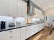 Gourmet kitchen featuring white cabinets, modern appliances, mosaic backsplash, and wood-look floors at 13706 Osprey Fern Ln, Riverview, FL 33569