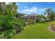 Landscaped backyard with a screened lanai, featuring lush tropical foliage and well-maintained lawn at 13872 Siena Loop, Lakewood Ranch, FL 34202
