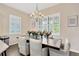 Elegant dining room featuring a chandelier, multiple windows with plantation shutters, and seating for six at 13872 Siena Loop, Lakewood Ranch, FL 34202