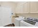 Functional laundry room with white washer and dryer, storage cabinets, and a utility sink at 13872 Siena Loop, Lakewood Ranch, FL 34202