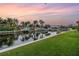 Waterfront backyard on a canal lined with docks, lush grass, and picturesque palm trees under a colorful sky at 1449 45Th Ne Ave, St Petersburg, FL 33703
