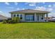 Home's rear exterior with a grassy yard, covered lanai, and sliding glass doors at 1599 Running Tide Pl, Sarasota, FL 34240