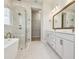 Bright bathroom with free-standing tub, glass shower, double sink vanity, and large mirror at 1599 Running Tide Pl, Sarasota, FL 34240