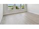 Bright bedroom featuring light wood-look flooring, three windows, and a view of water and palm trees at 1599 Running Tide Pl, Sarasota, FL 34240