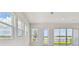 Bright living room with multiple windows and a glass patio door to a fenced lawn and serene water views at 1599 Running Tide Pl, Sarasota, FL 34240