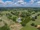 Aerial view of a sprawling property with green pastures, wooded areas, and a home with grey roof at 16326 Kalli Way, Dade City, FL 33523