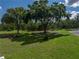Expansive backyard with manicured lawn, mature trees, a fire pit seating area, and an area for parking at 16326 Kalli Way, Dade City, FL 33523