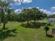 Expansive backyard with mature trees, green lawn, and a fire pit seating area at 16326 Kalli Way, Dade City, FL 33523