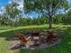A backyard fire pit surrounded by chairs and lush landscaping and trees at 16326 Kalli Way, Dade City, FL 33523