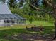 A backyard featuring a screened-in pool area and a fire pit seating area, surrounded by lush greenery and trees at 16326 Kalli Way, Dade City, FL 33523