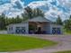 A large white barn with a central open bay, gravel driveway, and adjacent green lawn at 16326 Kalli Way, Dade City, FL 33523