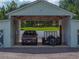Barn exterior showing a truck parked in the open bay, flanked by enclosed garages and gravel parking at 16326 Kalli Way, Dade City, FL 33523