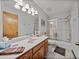 Bright bathroom featuring a single sink vanity, tiled floors, and a glass enclosed shower and tub at 16326 Kalli Way, Dade City, FL 33523