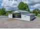 Exterior view of a grey shed with gravel driveway and attached lean-to under a cloudy sky at 16326 Kalli Way, Dade City, FL 33523