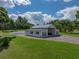 Aerial view of a white shed with grey trim, gravel driveway, green lawn, and shade trees at 16326 Kalli Way, Dade City, FL 33523