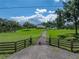 Wide shot of a lovely home with charming gate, expansive yard, and detached garage at 16326 Kalli Way, Dade City, FL 33523