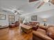 Living room featuring hardwood floors, multiple ceiling fans, plantation shutters, and leather furniture at 16326 Kalli Way, Dade City, FL 33523