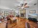Living room featuring hardwood floors, a brick fireplace, plantation shutters, and leather furniture at 16326 Kalli Way, Dade City, FL 33523