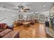 Living room featuring hardwood floors, leather furniture, plantation shutters, and a brick fireplace at 16326 Kalli Way, Dade City, FL 33523