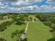 Aerial view of a property with expansive green lawns, mature trees, and a long driveway at 16326 Kalli Way, Dade City, FL 33523