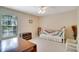 Bright bedroom features a bed with a patterned quilt, a desk, and a large window with blinds at 17321 Oak Ledge Dr, Lutz, FL 33549