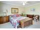 Bright bedroom with patterned bedspread, hardwood chest, bedside tables and neutral walls at 17321 Oak Ledge Dr, Lutz, FL 33549