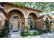 Inviting front entrance with arched doorway, complemented by well-manicured landscaping and neutral exterior colors at 17321 Oak Ledge Dr, Lutz, FL 33549