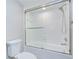 This is a bathtub and shower with white tile, glass doors and chrome fixtures at 17917 Clear Lake Dr, Lutz, FL 33548