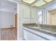 Bathroom with granite countertop, white cabinetry, large mirror, and a view to the bedroom and shower at 17917 Clear Lake Dr, Lutz, FL 33548