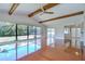 Bright living room with wood flooring, exposed beams, and views of the outdoor screened-in pool at 17917 Clear Lake Dr, Lutz, FL 33548