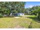 Wide view of the backyard, showing a blue house, trees, and partial fencing at 2305 N 48Th St, Tampa, FL 33605