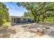 Single-story home with mature trees providing shade, plus a screened in porch, and blue front door at 2305 N 48Th St, Tampa, FL 33605